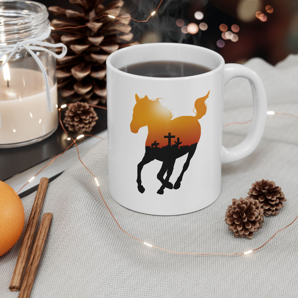 
                  
                    Load image into Gallery viewer, Mockup of a coffee mug featuring the silhouette of a running horse with an orange sky and crow outline in it
                  
                